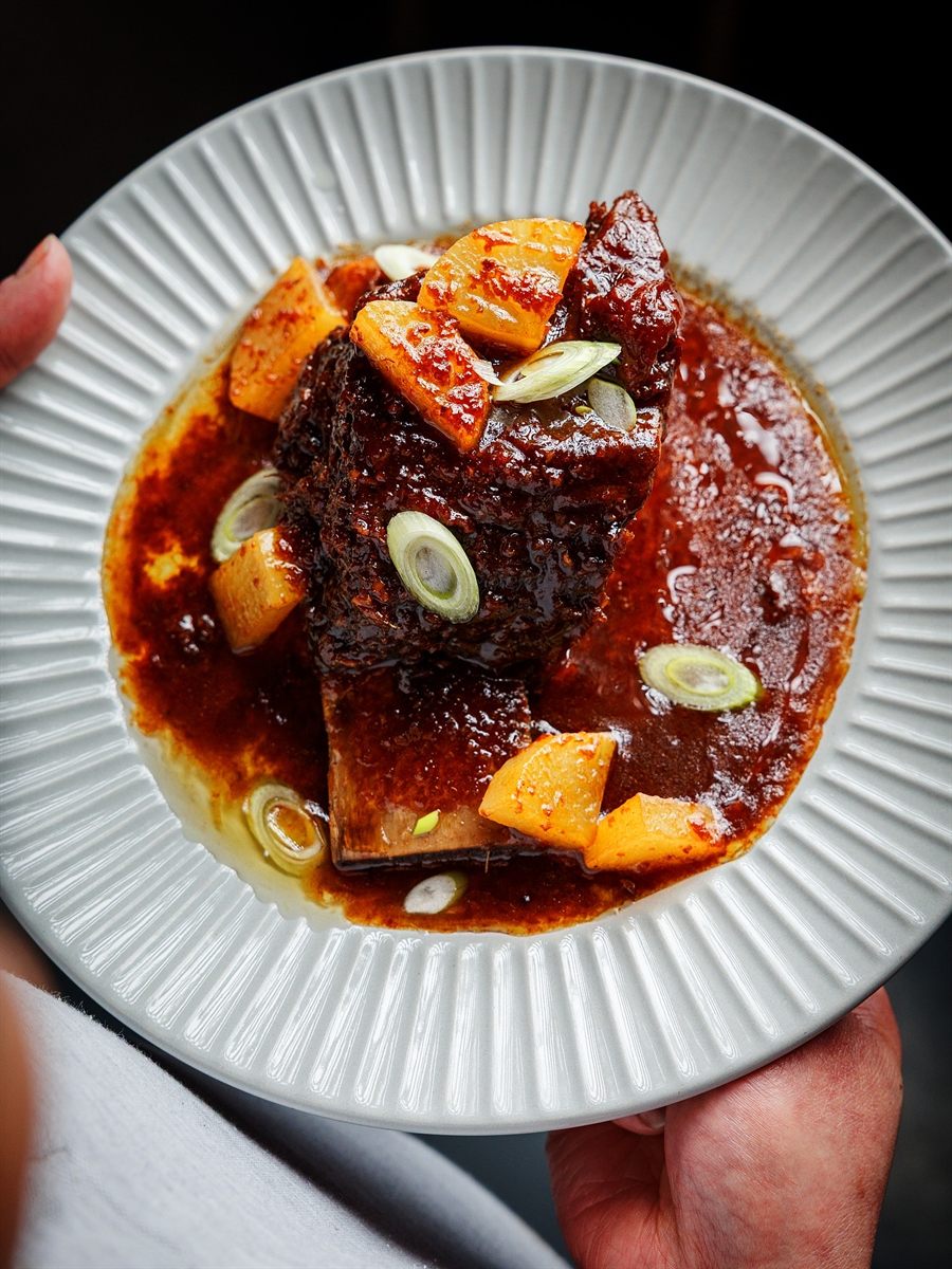 Overhead view of glazed pork belly in a rich sauce with spring onion